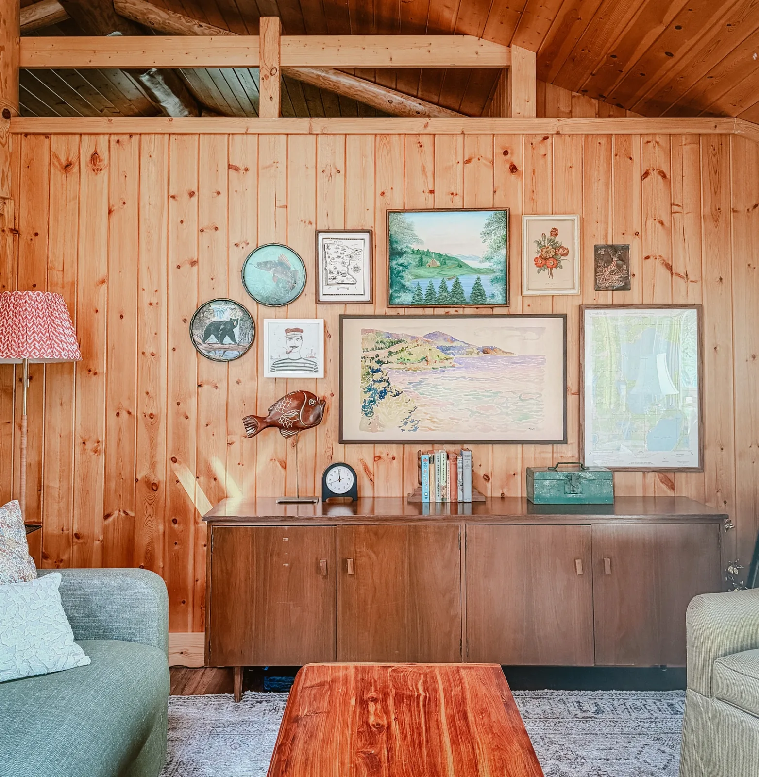 The living room art wall with vintage paintings and mid-century furniture