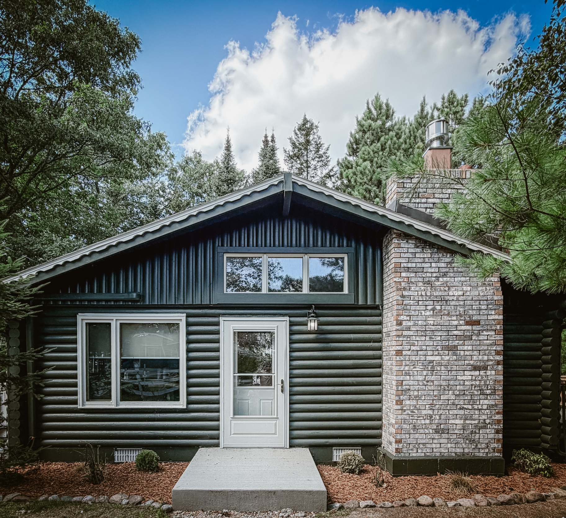 The dark green log cabin tucked among tall pines