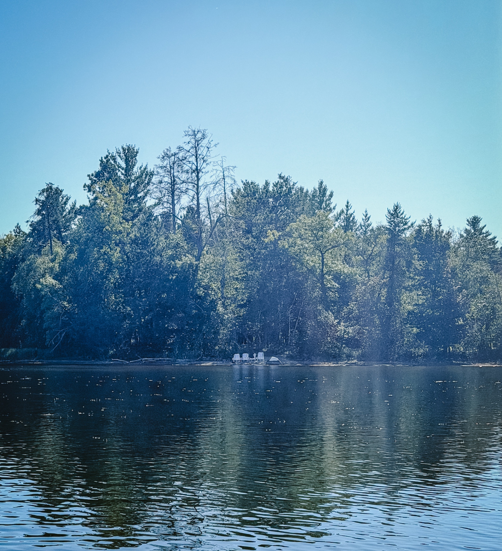 Beach chairs along the sandy shoreline, looking out over Little Pelican Lake