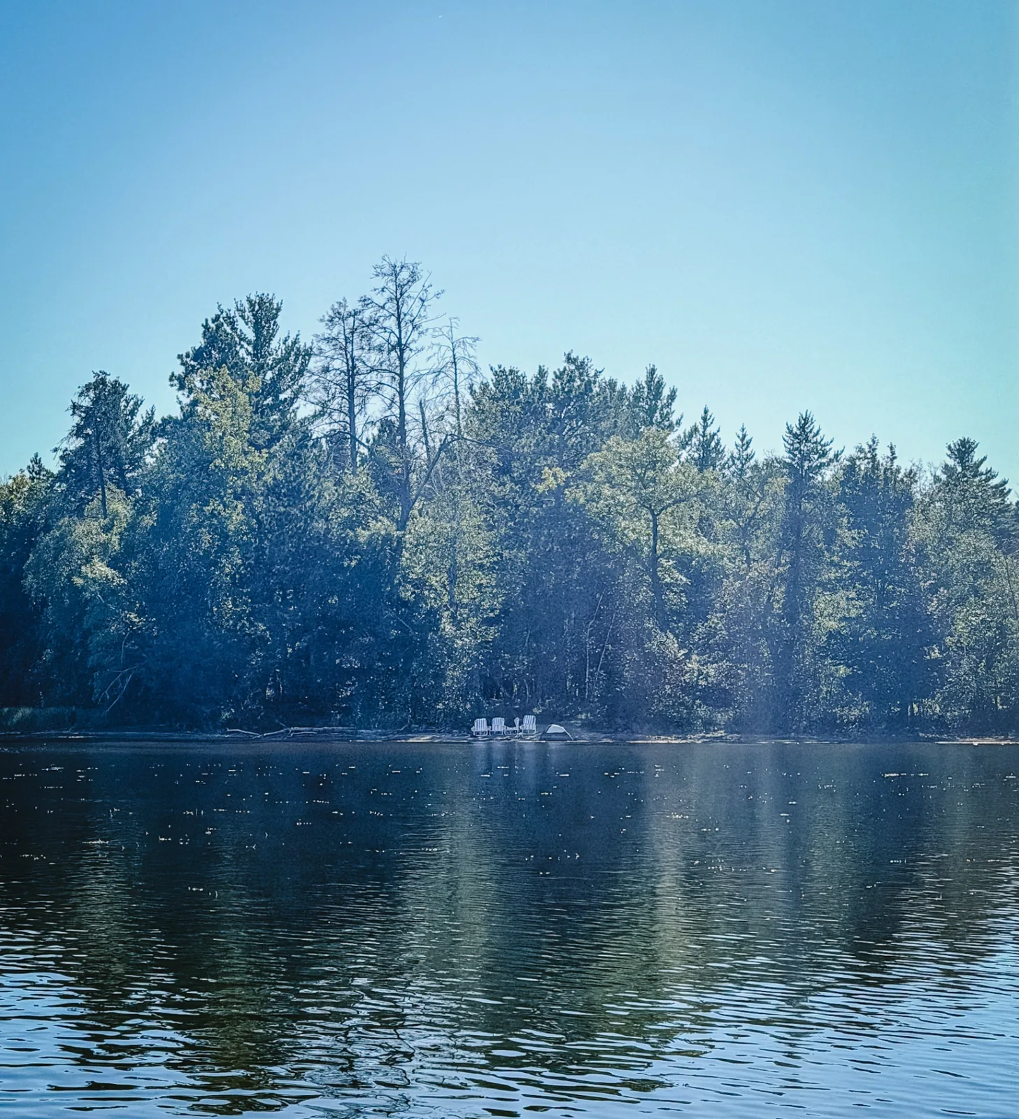 Beach chairs along the sandy shoreline, looking out over Little Pelican Lake