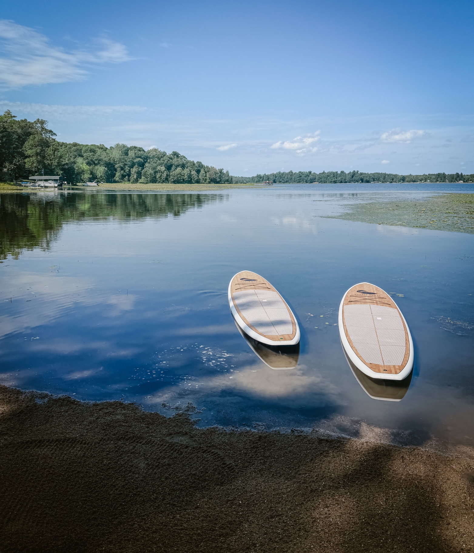 Two paddleboards floating on calm water at the cabin's sandy shore